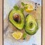 "Home Grown" is a mixed media artwork by Australian artist Jess King, featuring avocado halves, lemon, parsley and peppercorns painted in acrylic and pen over a vintage nautical chart of Moreton Bay.